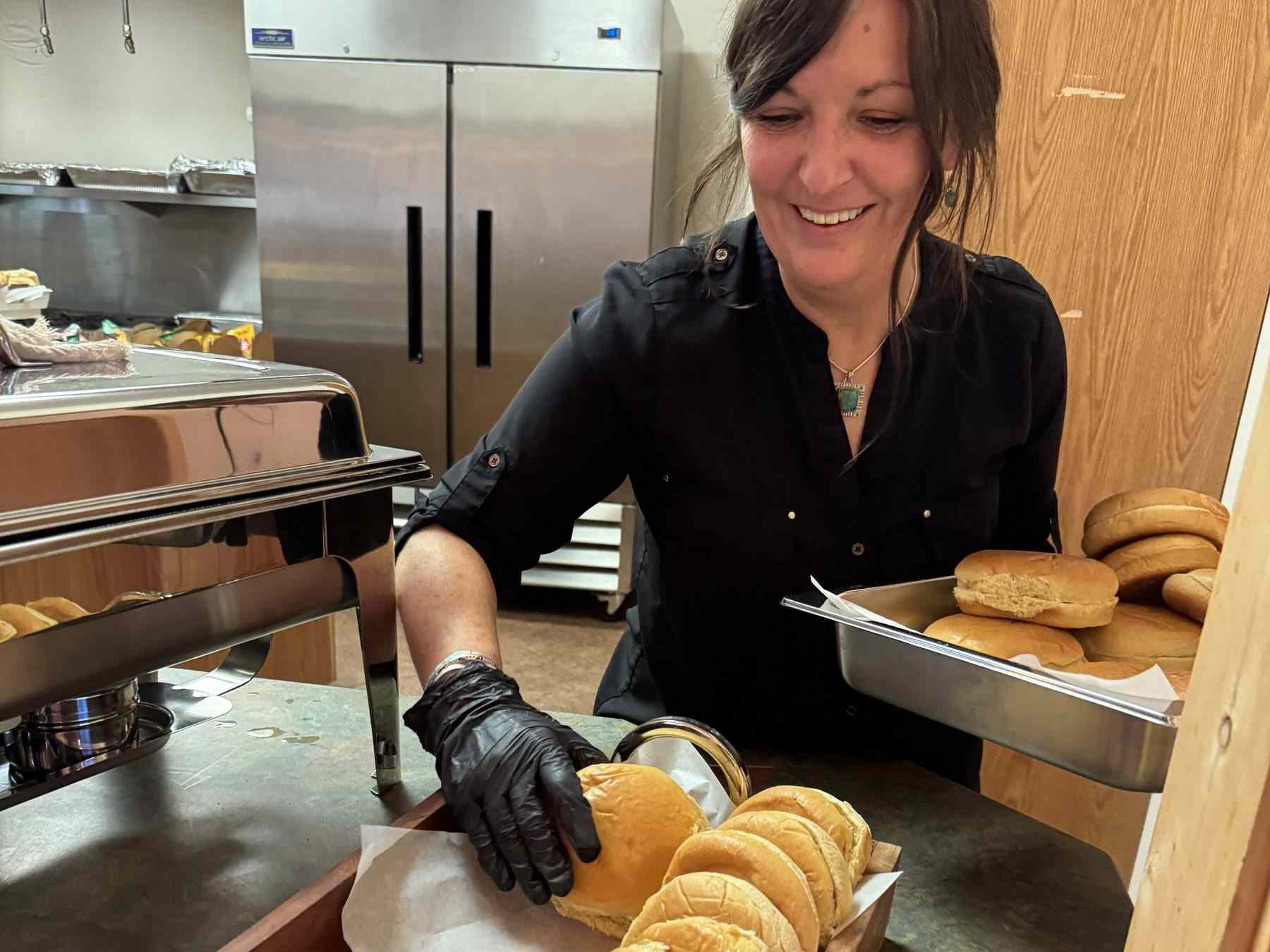 Aimee, in gloves, setting out buns on a wedding buffet