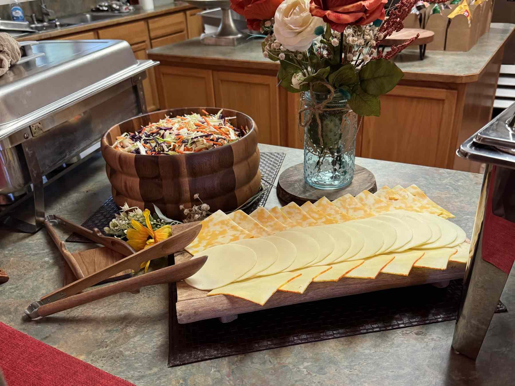 The wedding buffet: slaw, a sliced cheese board, sunflowers and roses