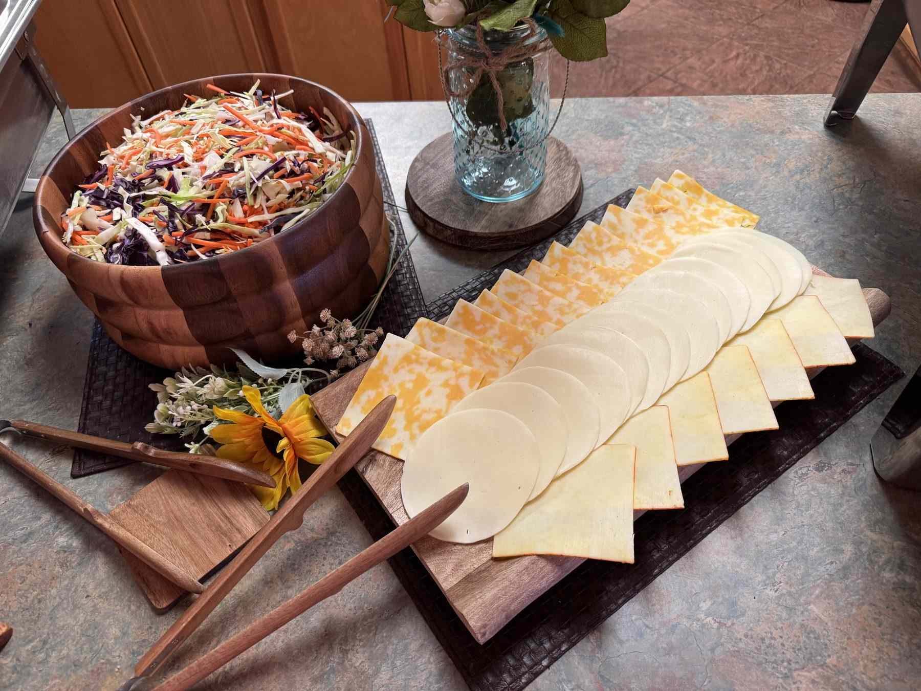 Slaw in a wooden bowl beside the cheese board